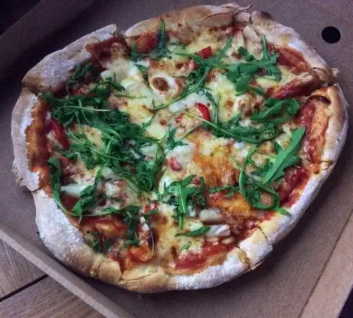 Freshly baked pizza topped with rocket and parmesan
